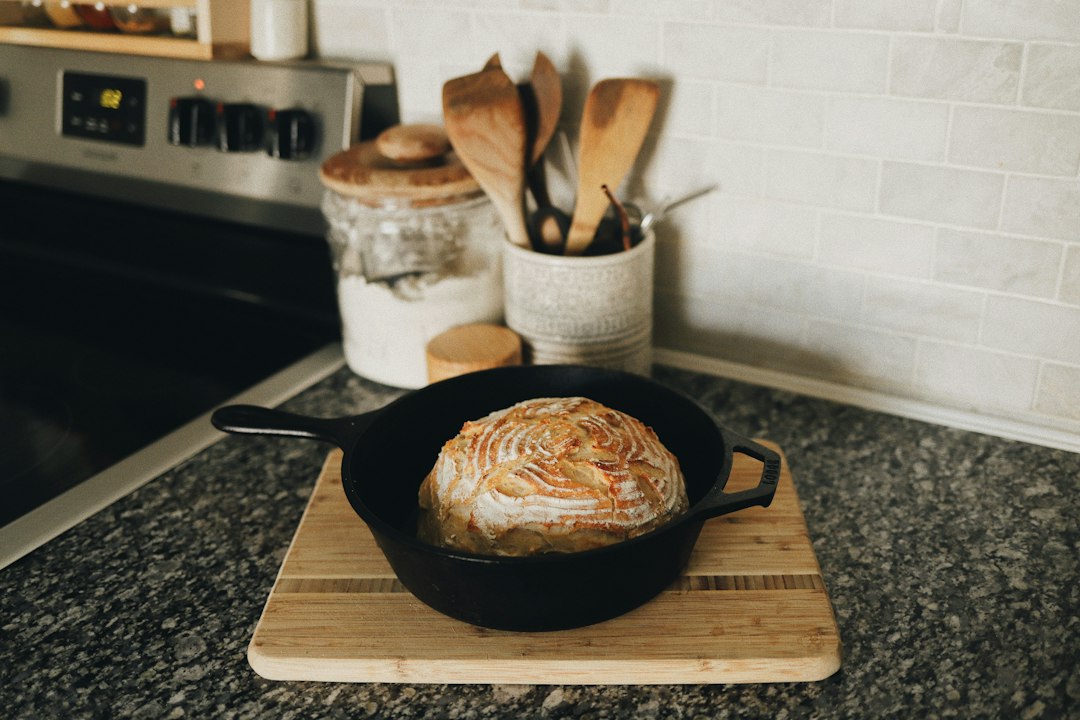 cast iron skillet care guide cover image showing a seasoned pan on a wooden board with a small oil bottle and towel
